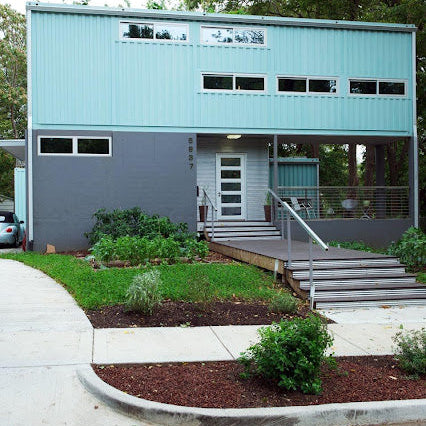 Modern two-story building with a blue exterior and greenery around.