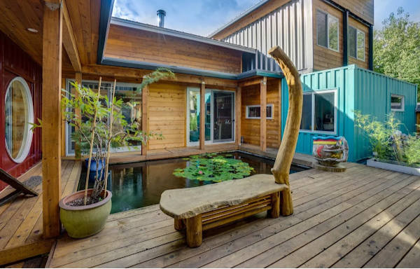 Modern house with a wooden deck, pond, and decorative elements.