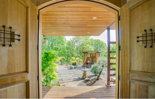 Wooden doors open to reveal a garden with a small wooden structure.