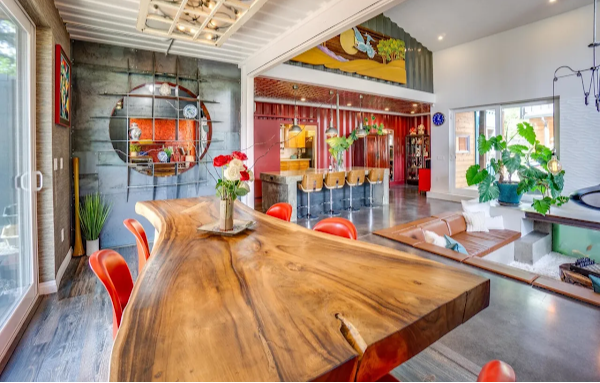 Modern interior with a wooden dining table and red chairs in a well-lit room.