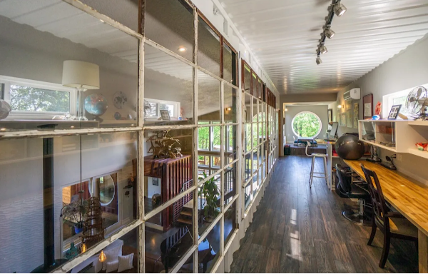 Long hallway with glass walls, wooden floor, and various decor elements.
