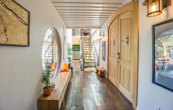 Hallway with wooden door, round mirror, and decorative items.