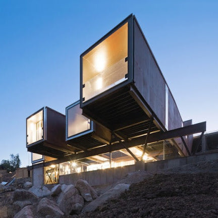 Modern architectural structure with glass panels and concrete elements against a clear sky.