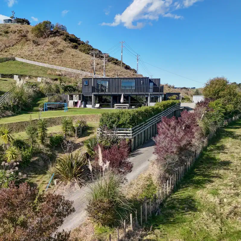 Modern house on a hillside with greenery and clear sky