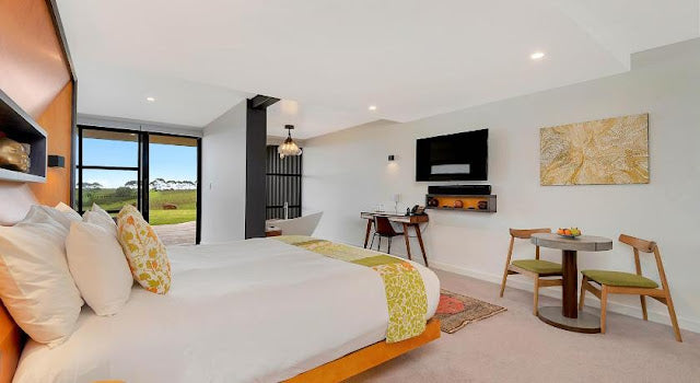 Modern bedroom with a bed, television, and small dining area.