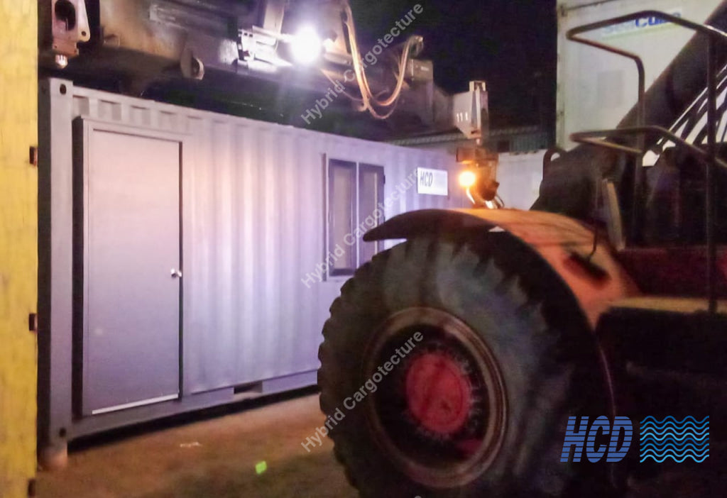 Close-up of a large industrial vehicle tire with a container in the background