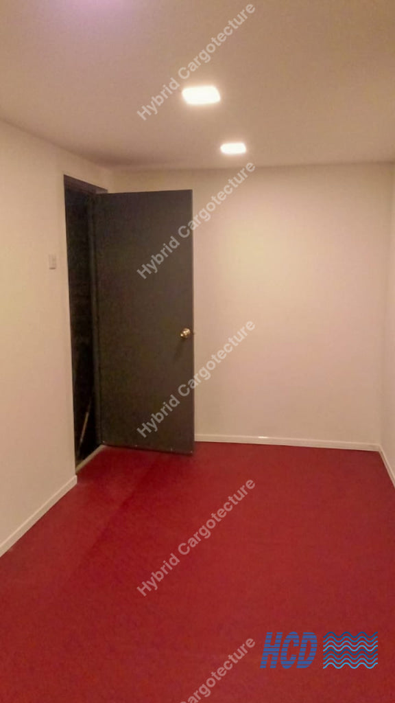 Empty room with red carpet, white walls, and a closed door.