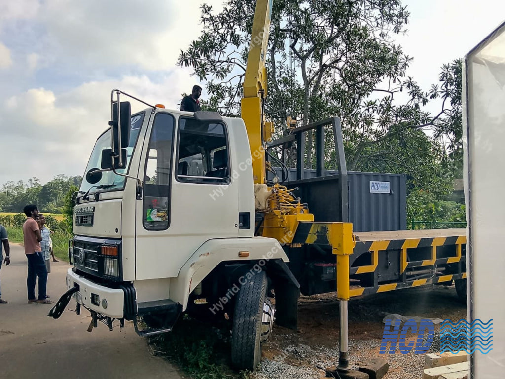 White truck with a crane attachment on a road with people around